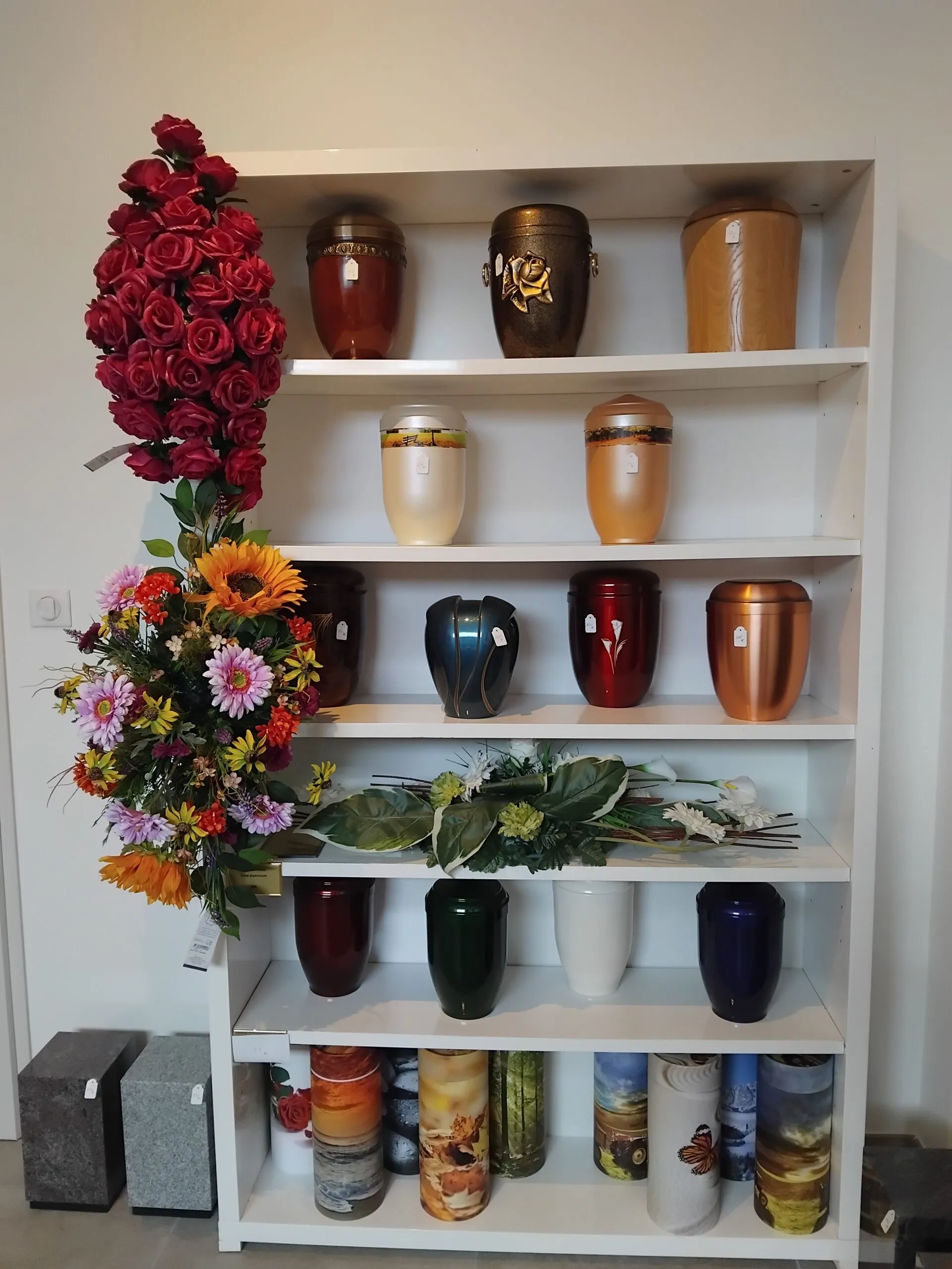présentation d'urnes cinéraires variées et compositions florales de deuil